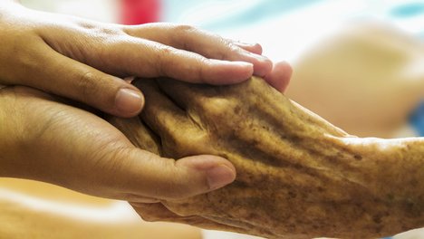 Das Foto zur Pressemitteilung der Linken NRW zum Tag der Pflege zeigt die Hände einer Pflegekraft, die die eines alten Menschen halten.